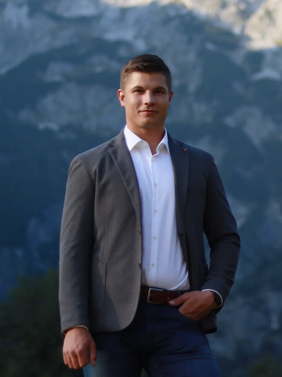 Lukas Meissnitzer M. Sc. im Sakko vor der Bergkulisse des Pongaus